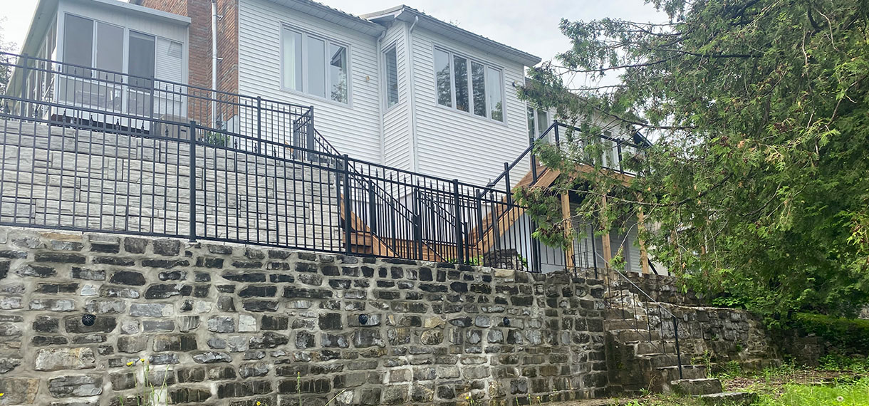 Retaining Wall With Wrought Iron Fence & Wooden Steps With Railings